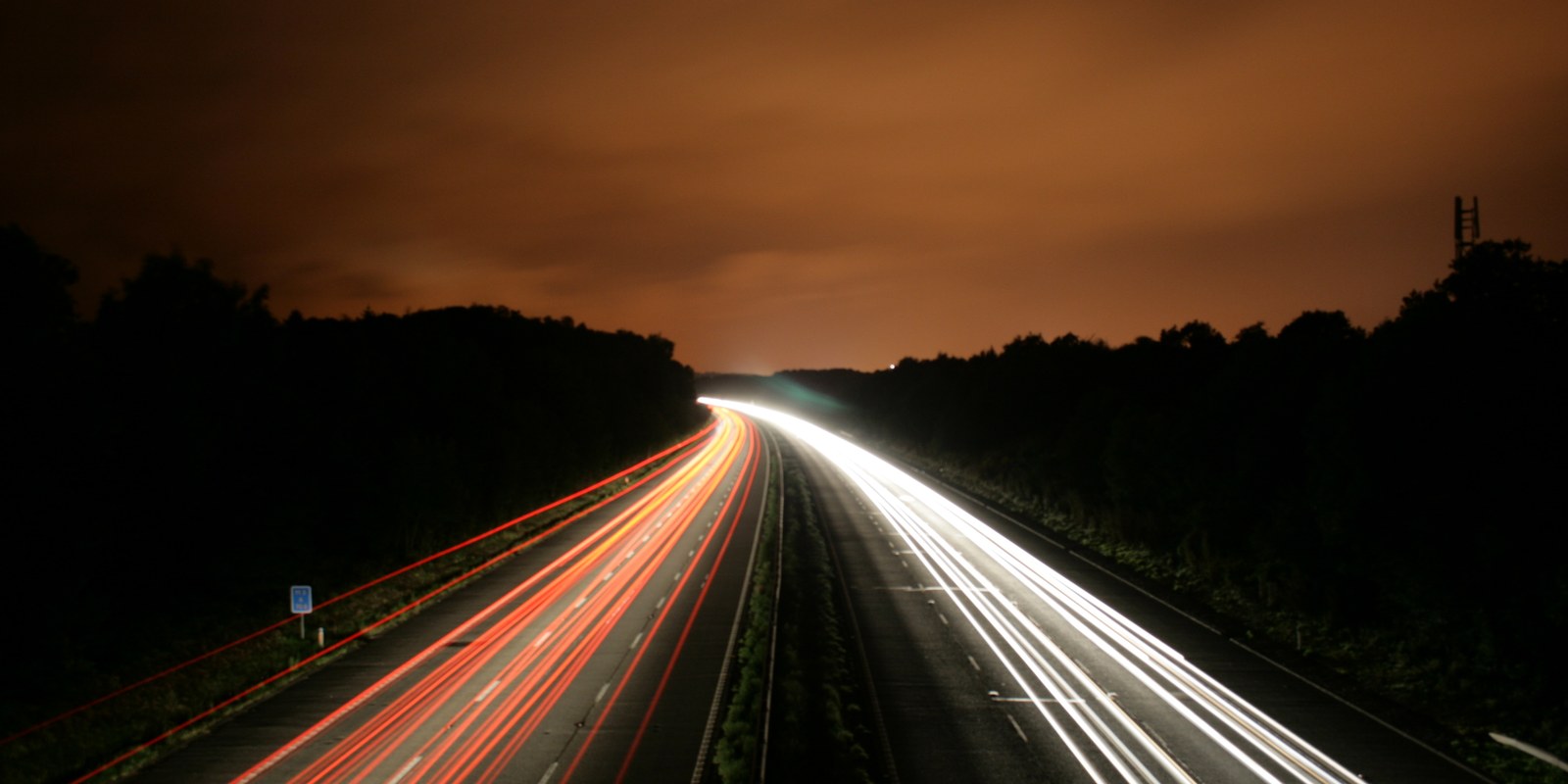 Photograph of the M3 motorway at night, car light trails drawing continuous lines along the carriageways ("M3 at Night 1" by Simon Green, CC BY-SA 2.0)